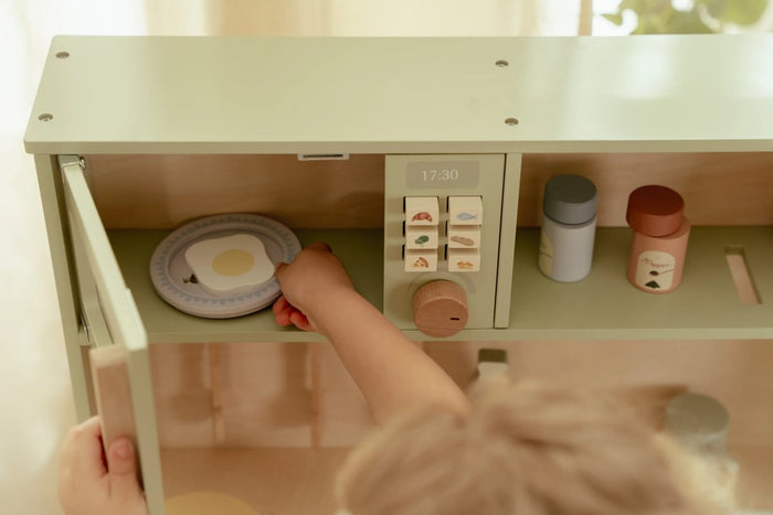 Kind spielt an einer mintfarbenen Holz-Spielküche – Rollenspiel im Kinderzimmer
